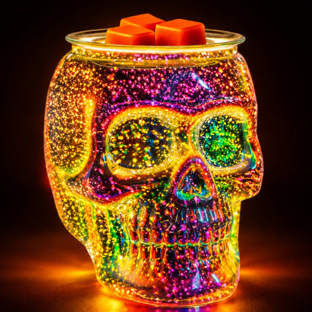 Glass skull wax warmer glowing with multicolored light, with orange wax melts in the top dish.