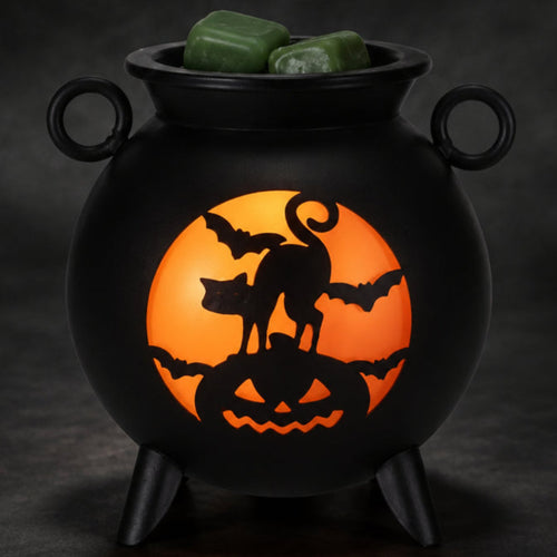 Black cauldron wax warmer glowing orange with a black cat, bats, and jack-o’-lantern design.