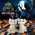 Bone white skeleton kitty and puppy candles with black eyes, displayed in a Halloween scene with pumpkins, a full moon, and an owl.